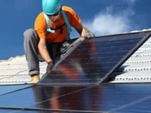 arbeider plaatst zonnepanelen op hellend dak